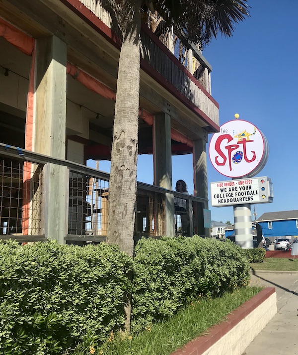 The entry to a restaurant with a round sign that reads The Spot on Galveston Island Texas