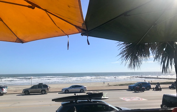 A view of the beach seen through an orange and a black umbrella on Galveston Island Texas