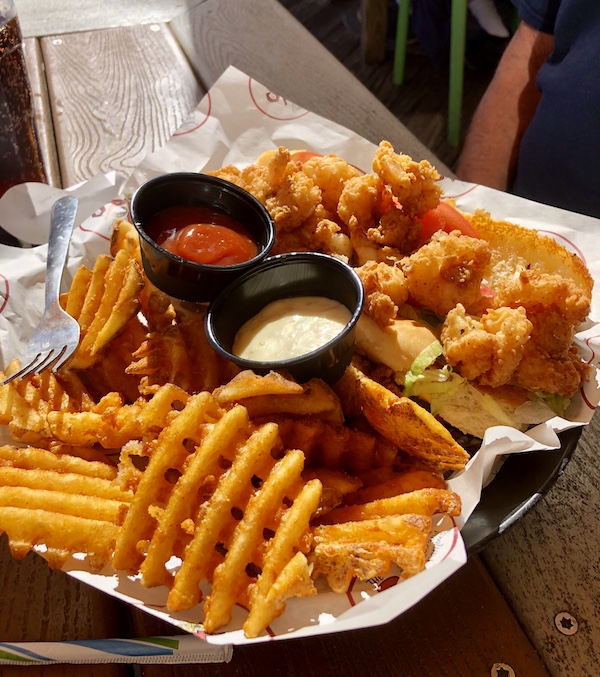 A basket filled with a fried shrimp sandwich and waffle fries at a restaurant on Galveston Island Texas