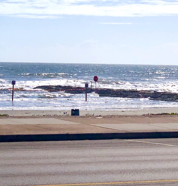 A beach with a jetty and water on Galveston Island Texas