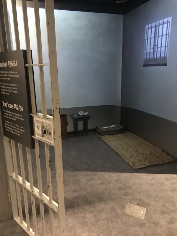 A jail cell with a straw mat on the floor to sleep on at the Holocaust Museum Houston