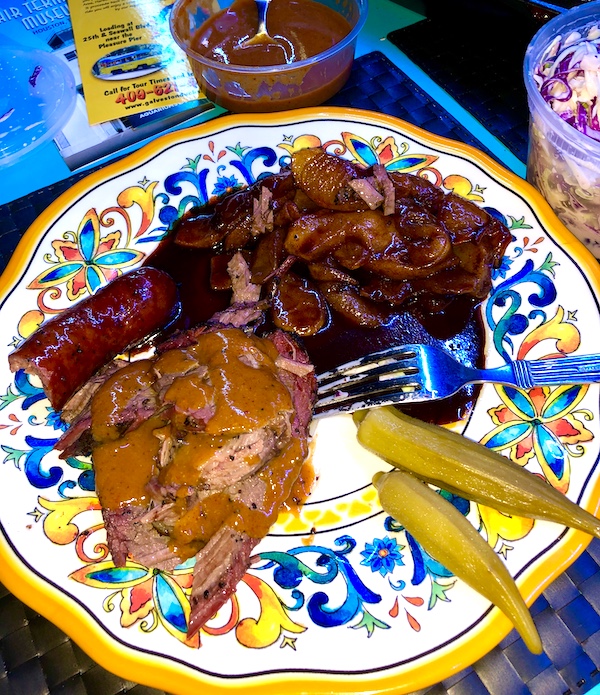 A colorful plate topped with sausage, sliced meat, okra and cooked apples from a restaurant near the Holocaust Museum Houston