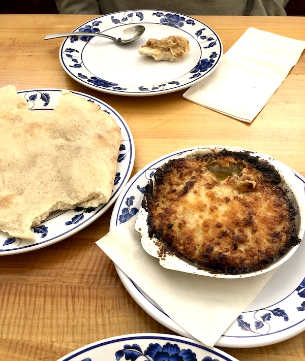 A casserole with crusty top and pita bread on blue and white plates in Southwestern Louisiana