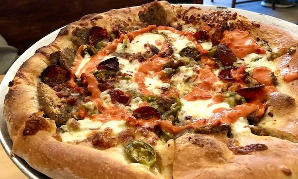 An aluminum pizza pan topped with a whole pizza in Southwestern Louisiana