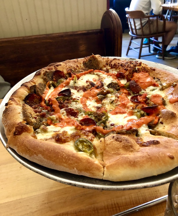 An aluminum pizza pan topped with a whole pizza in Southwestern Louisiana