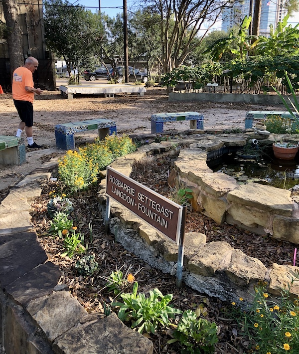 A man in an orange shirt by a circular tiered fountain at The Houston Center for Contemporary Craft
