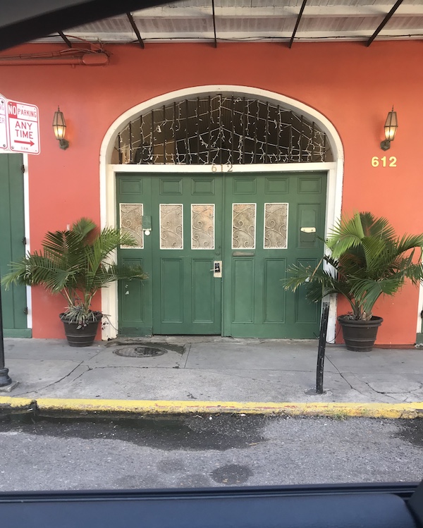 Tidbits of Life in New Orleans a coral colored building with green doors.