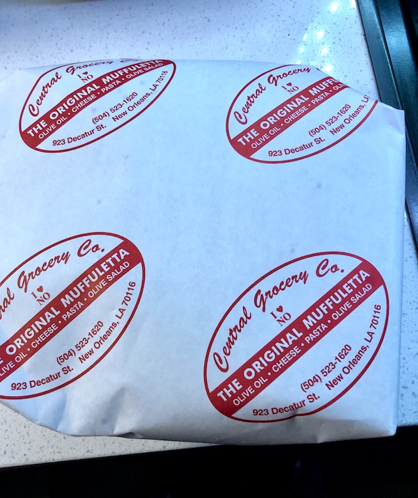 Tidbits of Life in New Orleans white paper with red writing that is wrapping a sandwich