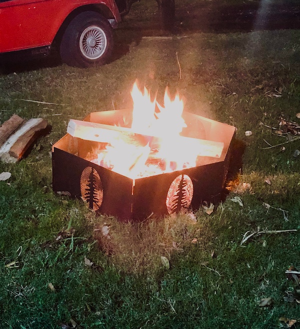 Tidbits of Life in New Orleans a blazing fire in a black fire pit on a lawn.