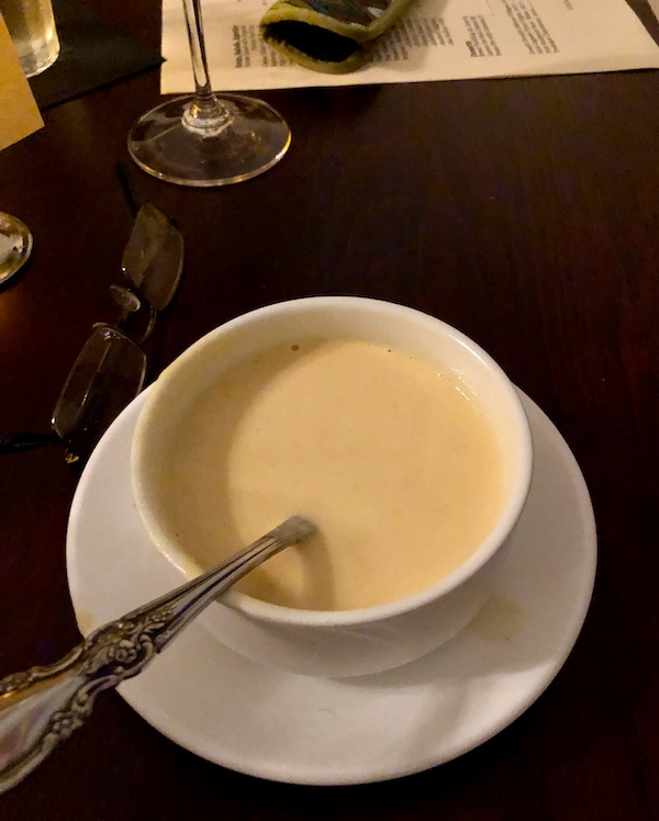 Tidbits of Life in New Orleans a white bowl filled with creamy soup and a spoon on a white plate.