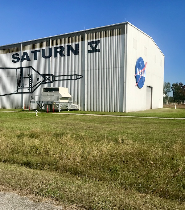 A white corrugated metal building that houses the Saturn V Rocket at NASA Space Center Houston