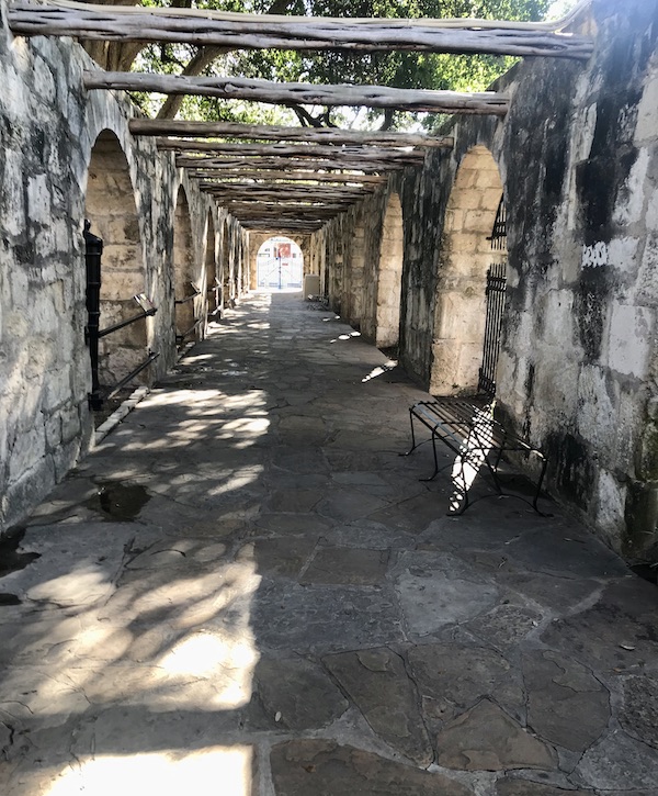 An arcade creates a walkway by the Alamo