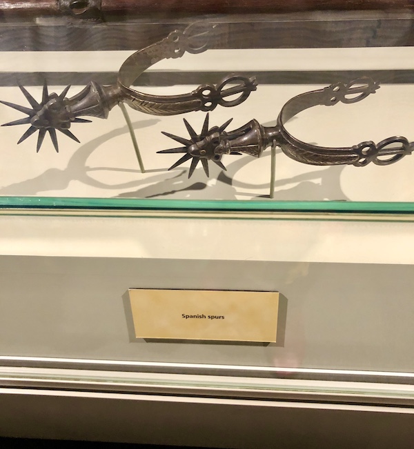 A display case with a pair of old spurs help us Remember the Alamo