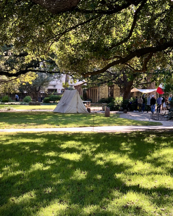 A lawn with a white teepee tent helps us Remember the Alamo