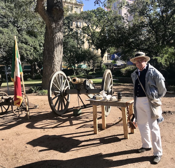 A man in a straw hat standing near a canon helps us Remember the Alamo