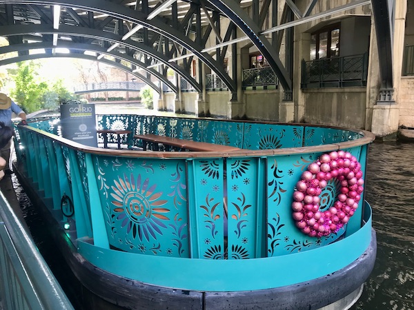 A turquoise river boat with pink wreath for our San Antonio River Cruise