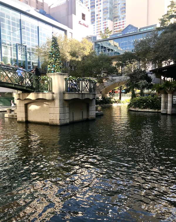Trees, buildings and river are the starting point of our San Antonio River Cruise