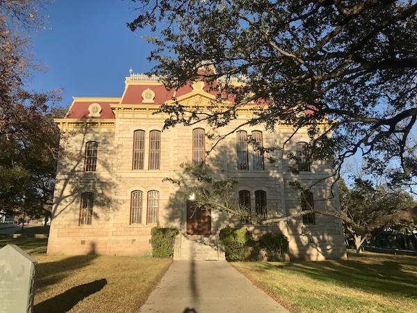 A tan building with a red roof and trees in Sonora Texas