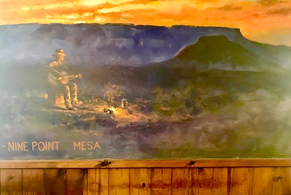 A mural of a play guitar by a fire with mountain in back at Terlingua Ranch Texas
