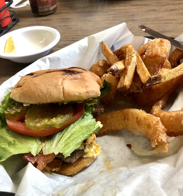 A large plate topped with a burger and fries sitting on deli paper at Terlingua Ranch Texas