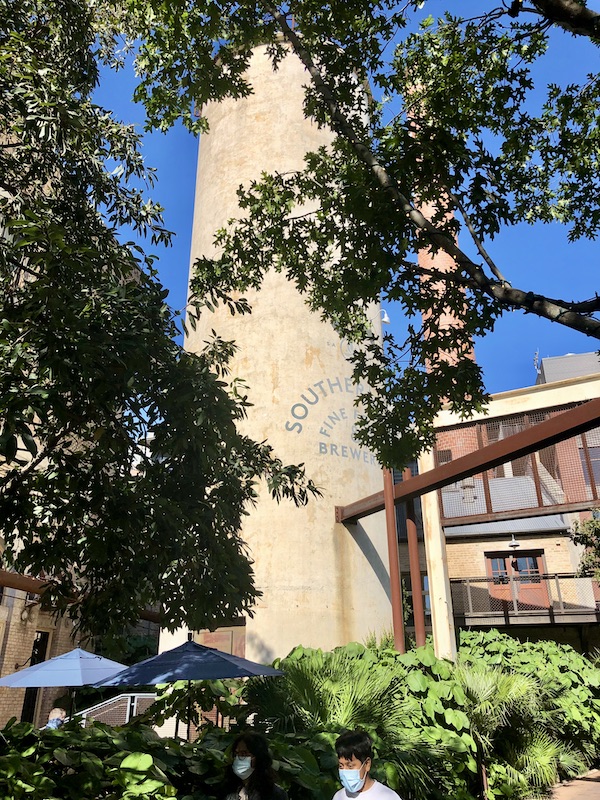 Large beige stucco smoke stack with Southerleigh Brewery written on it and landscaping surrounding it at The Pearl in San Antonio