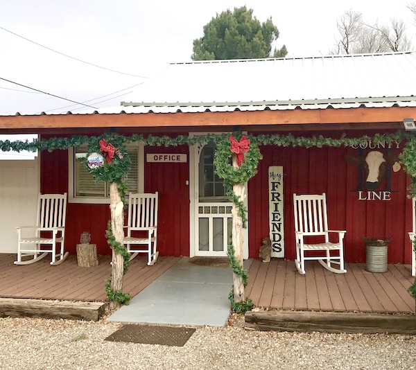 A red building with white rocking chairs on the porch where we are checking to see if Aliens Abound in Roswell New Mexico