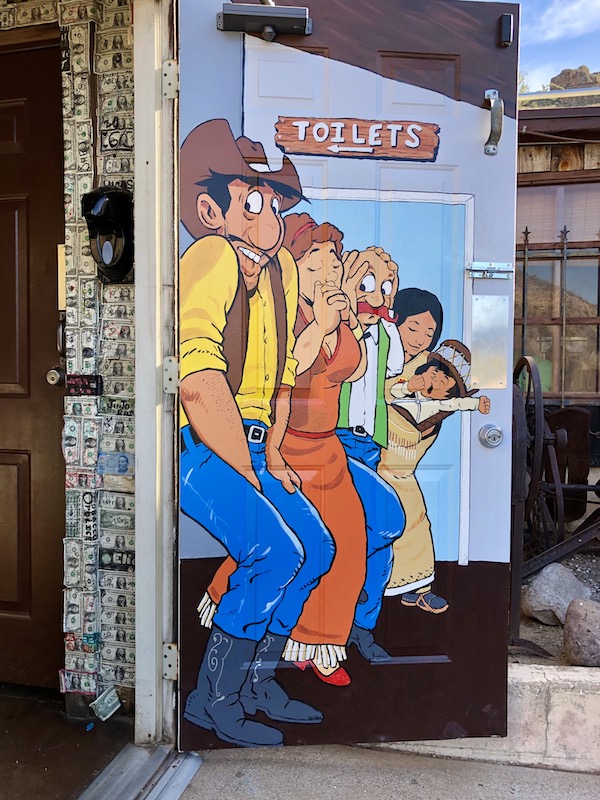 A colorful painting of a cowboy, a woman, a man with a mustache and an Indian woman with a child, on an entry door seen along the Apache Trail Arizona