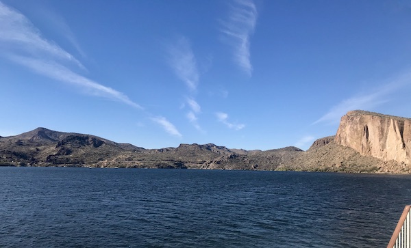 Mountains surrounding a lake with blue sky and wispy clouds along the Apache Trail Arizona