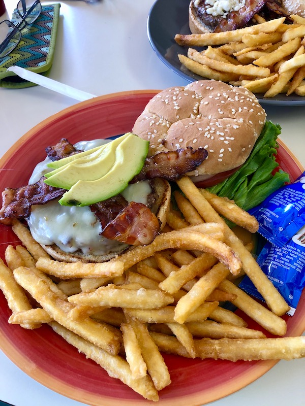 A cheeseburger with bacon and avocado with a side of fries on a red plate in Bisbee Tombstone and Boot Hill in Arizona