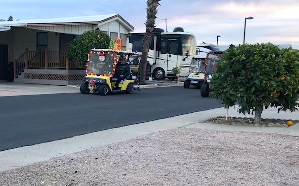 A couple of decorated golf carts passing RVs and Park model homes at Mesa Regal RV Resort