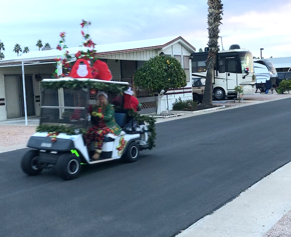 A golf cart decorated for Christmas rides on the street of Mesa Regal RV Resort