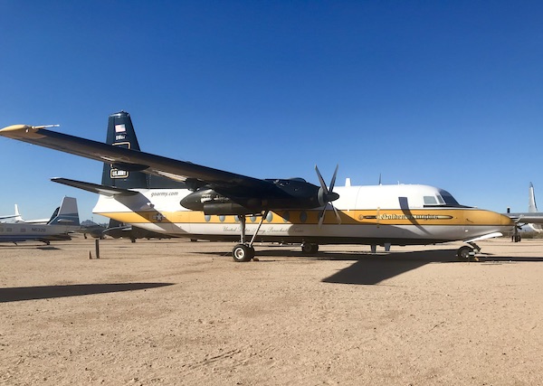 A white and gold Army airplane with propeller engines on display at the Pima Air and Space Museum