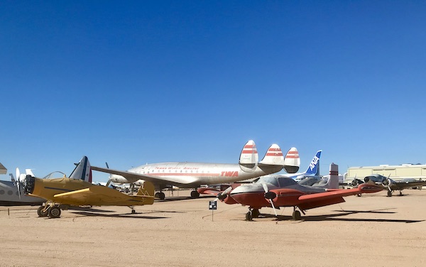 A couple of small airplanes in front of a TWA airplane at the Pima Air and Space Museum