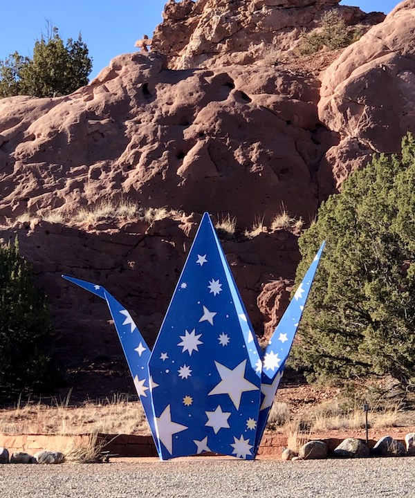 A blue and white origami sculpture in front of a mountain along our drive from Santa Fe to Albuquerque New Mexico