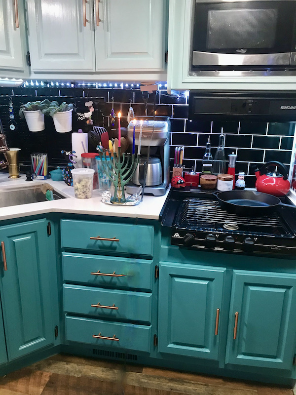A teal and black kitchen with white countertop and a Hanukah menorah with 3 candles lit after our drive from Santa Fe to Albuquerque New Mexico