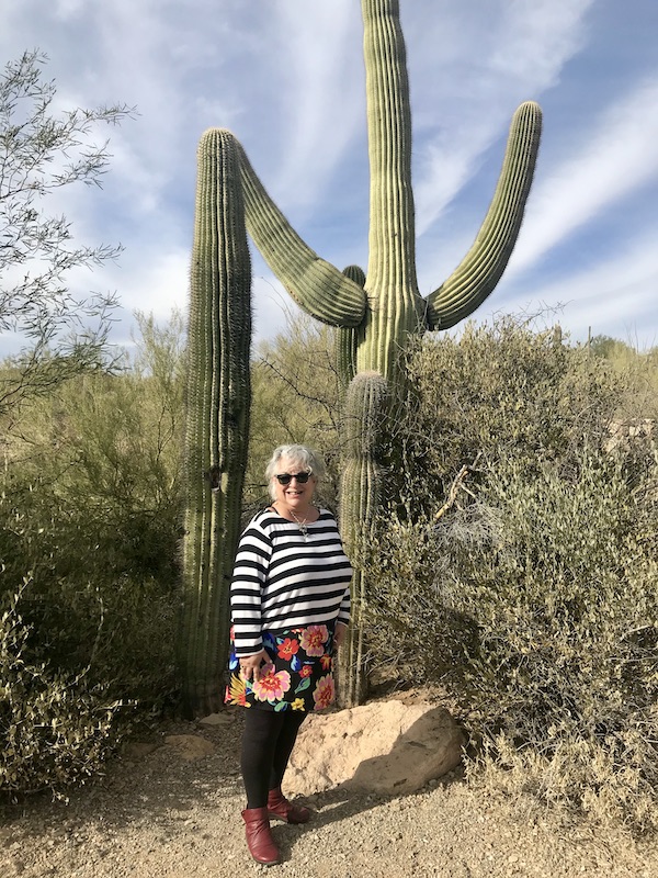 A woman in a striped top standing between two tall cactus at the Sonoran Desert Museum