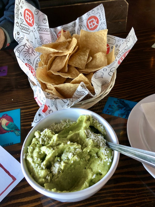A white bowl of guacamole with a spoon and a basket of tortilla chips on our way to the Sonoran Desert Museum
