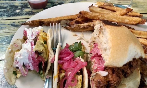 A white plate topped with 2 breakfast tacos and half of a fried chicken sandwich and fries at The Waterstop Marfa Texas