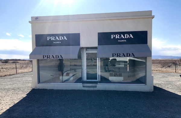 A white build with awnings that say Prada just past The Waterstop Marfa Texas