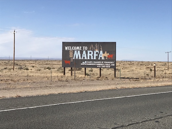 A brown road sign with white letters welcomes you to Marfa Texas.