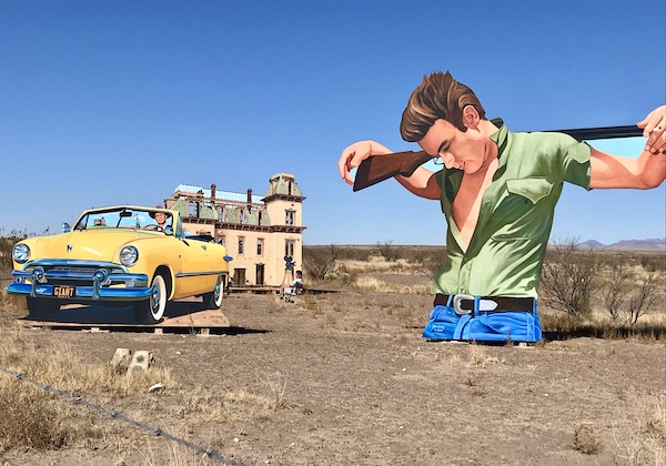 A larger than life cut out of a man in a green shirt just past The Waterstop Marfa Texas