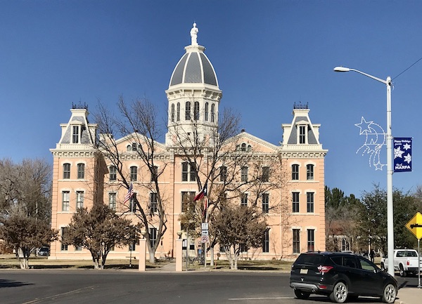 A pink multistory building is Presidio County Courthouse in Marfa Texas 