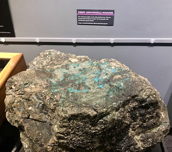 A large rock that is tan, with turquoise markings and sparkly white spots on display at the Arizona Museum of Natural History