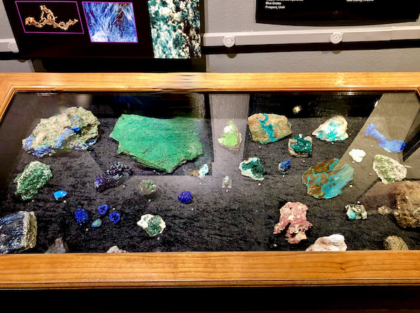 A glass case with wood frame and black lining topped with blue and green rocks at the Arizona Museum of Natural History