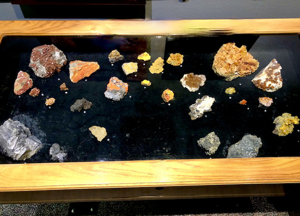A glass case with wood frame and black lining topped with orange and yellow rocks at the Arizona Museum of Natural History