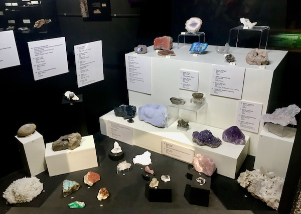 A glass case with cream colored risers displaying a variety of quartz at the Arizona Museum of Natural History