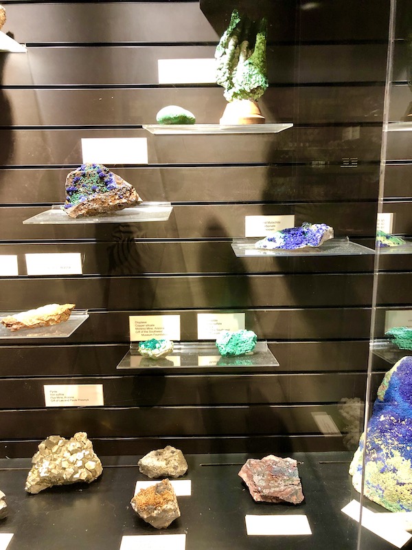 A glass case with shelves holding quarts rocks in many colors on display at the Arizona Museum of Natural History