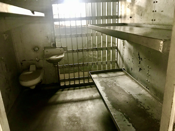 The interior of a jail cell with two metal bunks, a sink and toilet at the Arizona Museum of Natural History