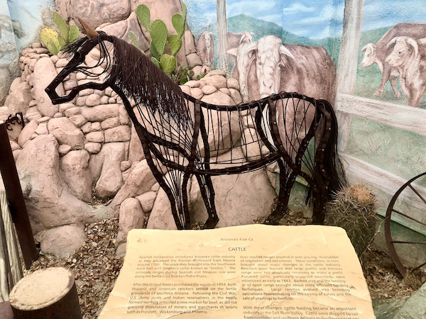 A metal sculpture of a horse in front of a mural with rocks, paddle Cactus and cattle at the The Fremont Street Experience located in downtown Las Vegas Nevada. Visit https://TheTravelingLocavores.combo follow our adventures #downtownlasvegas #fremontstreetexperiance #RVTravels #LasVegas #TheTravelingLocavores #Wanderlust #heartattackgrill #whitecastleburgers #goldennugget #Foodblog #Travel #neonlights