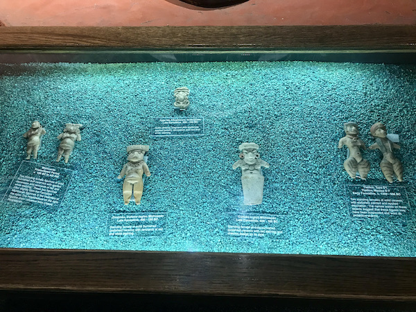 A glass case filled with turquoise gravel and Mayan artifacts at the The Fremont Street Experience located in downtown Las Vegas Nevada. Visit https://TheTravelingLocavores.combo follow our adventures #downtownlasvegas #fremontstreetexperiance #RVTravels #LasVegas #TheTravelingLocavores #Wanderlust #heartattackgrill #whitecastleburgers #goldennugget #Foodblog #Travel #neonlights
